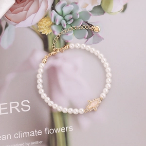 White pearl bracelet with golden Hamsa Hand pendant and adjustable heart extension chain