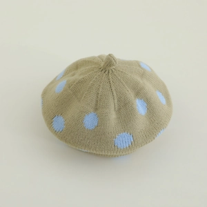 Detail of knitted beige beret with blue polka dots and a classic top loop for kids
