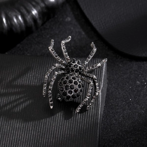 Macro shot of spider brooch with black rhinestones on a textured jewelry gift box