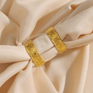 Vintage golden star and moon embossed rings displayed on soft beige silk fabric background