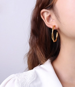 Close-up of a model wearing the 18k gold-plated twisted double-layer hoop earrings