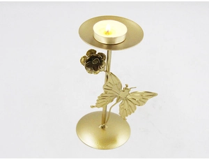 Detailed close-up of golden iron candle holder with delicate butterfly and flower accents
