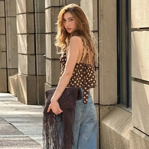 Vue de rue détaillée du caraco marron à pois avec jean bleu et sac tissé à franges