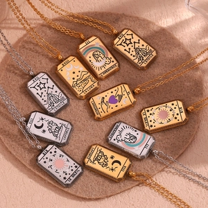 18K gold and silver tarot card necklaces displayed on a stone tray in studio light