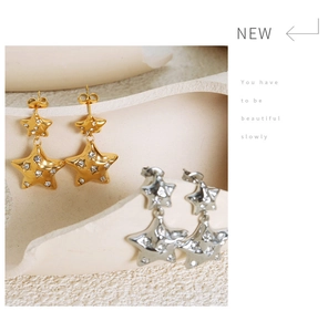 Close-up of gold and silver layered star earrings with sparkling zircon inlay details