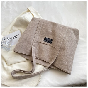 Khaki canvas tote bag with black fashion patch on a stylish white suit jacket