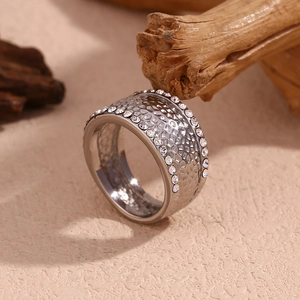 Close-up of silver hammered texture ring with white crystal inlay on a beige surface