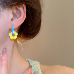 Close-up of model wearing colorful resin flower earrings with yellow petals and blue hoops