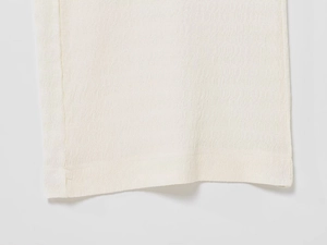 Dettaglio del tessuto a maglia bianco crema con trama ondulata e cucitura dell'orlo