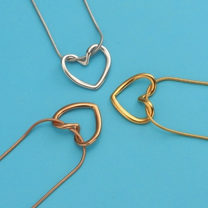 Three stainless steel heart pendant necklaces in silver, gold, and rose gold on blue background