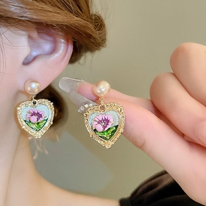 Macro view of vintage heart earrings with pink enamel flowers and pearls on ears