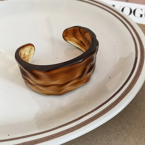 Macro detail of acrylic resin cuff with amber tortoiseshell texture and wavy edges