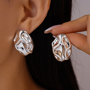 Macro shot of liquid metal style silver irregular earrings with glossy fluid texture