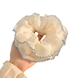 Off-white scrunchie with blue wavy stitching detail held against white background