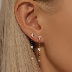 Detail of elegant gold tassel earrings with three teardrop cubic zirconia on a model