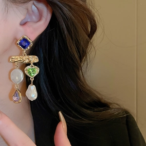 Close-up of vintage court style asymmetrical earrings with faux pearls and colorful gems
