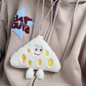 Detail of plush cheese coin purse with cute cartoon face on a beige hoodie background