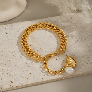 Détail du pendentif coquillage doré et perle sur bracelet gourmette en acier