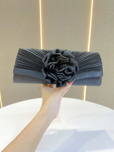 Black pleated evening clutch bag featuring a stunning fabric flower for elegant banquets.