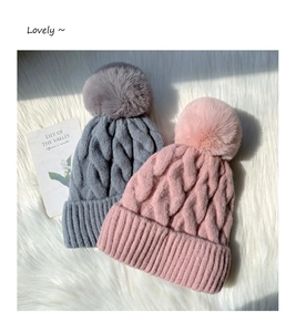 Detailed macro view of chunky cable knit texture and large fluffy pom-poms on winter beanies