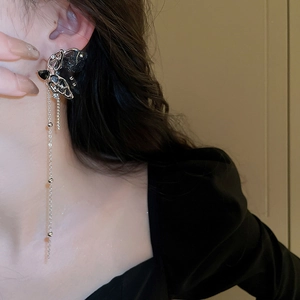 Detailed view of long black butterfly tassel earring with silver chain on model