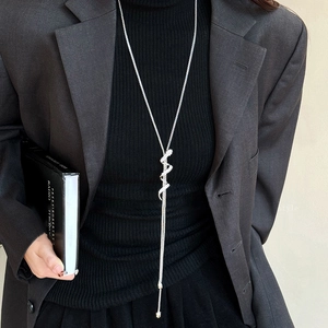 Silver snake pendant necklace with rhinestones worn on a black knit sweater