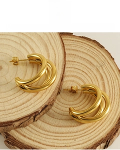 Detailed close-up of 18K gold plated multi-layer hoop earrings on a rustic wood background