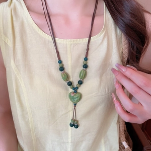 Détail d'un pendentif cœur en céramique verte avec cordon tressé et accents de perles