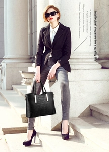 Close-up of black crocodile embossed tote bag featuring elegant light gold metal hardware