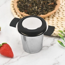 Close-up of a stainless steel tea infuser with black silicone handles on marble background