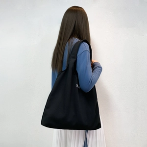 Vue arrière d'un mannequin portant un grand sac cabas noir en toile avec imprimé Simplicity