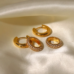 Elegant gold titanium earrings set with full diamonds on silk fabric backdrop