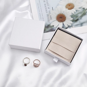 Detail of luxury white jewelry gift box and beige microfiber suede pouch on silk