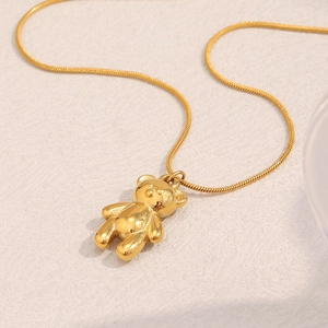 Detail of 18K gold plated bear pendant with fine snake chain and smooth metallic finish