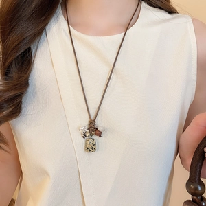 Detail view of a long vintage beaded necklace with spotted stone pendant on a model