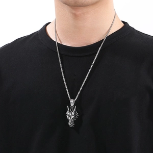 Detail of silver dragon pendant necklace worn by male model on white background