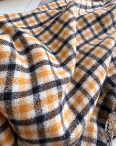Close-up of soft orange and black plaid cashmere texture scarf with warm fringe detail