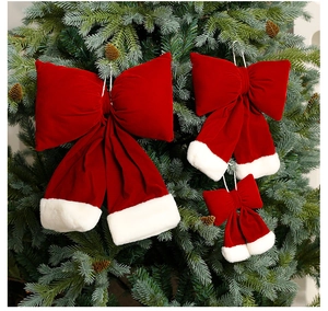 Detail of burgundy velvet Christmas bows with faux fur trim hanging on a pine tree branch