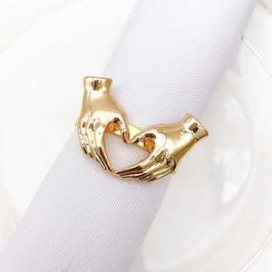 Detailed view of golden heart gesture metal napkin ring on white dinner cloth