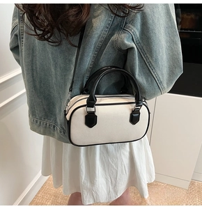 Detail of contrast color crossbody bag with black handles and adjustable strap