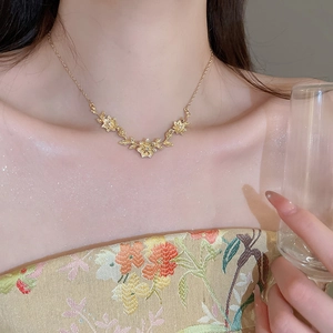 Close-up of gold flower and leaf pendant necklace with micro-pave zircons on a model
