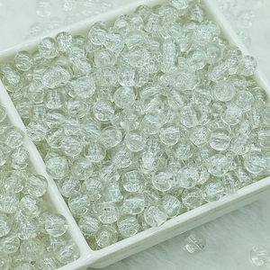 Macro shot of clear cracked glass round beads for DIY jewelry making in a white tray