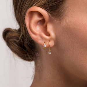 Detail of gold crystal drop hoop earrings worn by a model in a close-up lifestyle view