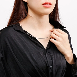 Close-up of minimalist silver titanium steel C-shape collar necklace on model neck