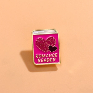 Detail of pink book enamel pin with glitter hearts and Romance Reader gold text