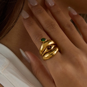 Detailed view of stacked gold zircon rings featuring green marquise and red heart stones