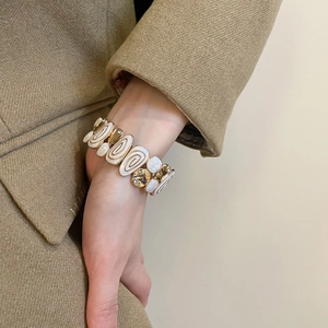 Detail of vintage gold stretch bracelet with white enamel spiral patterns and crystals