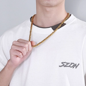 Gros plan d'une chaîne byzantine dorée pour homme sur un mannequin portant un t-shirt blanc