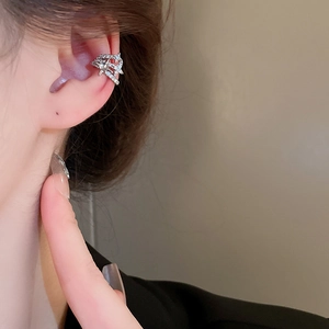 Nahaufnahme einer geschichteten silbernen Ohrmanschette mit Zirkonia-Akzenten am Ohr