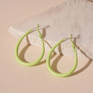 Detail of light green oval hoop earrings resting on an off-white natural stone